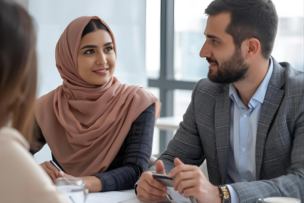 Image of a man and woman talking at an office desk. The image represents the course Effective Leadership for Mental Health In The Workplace
